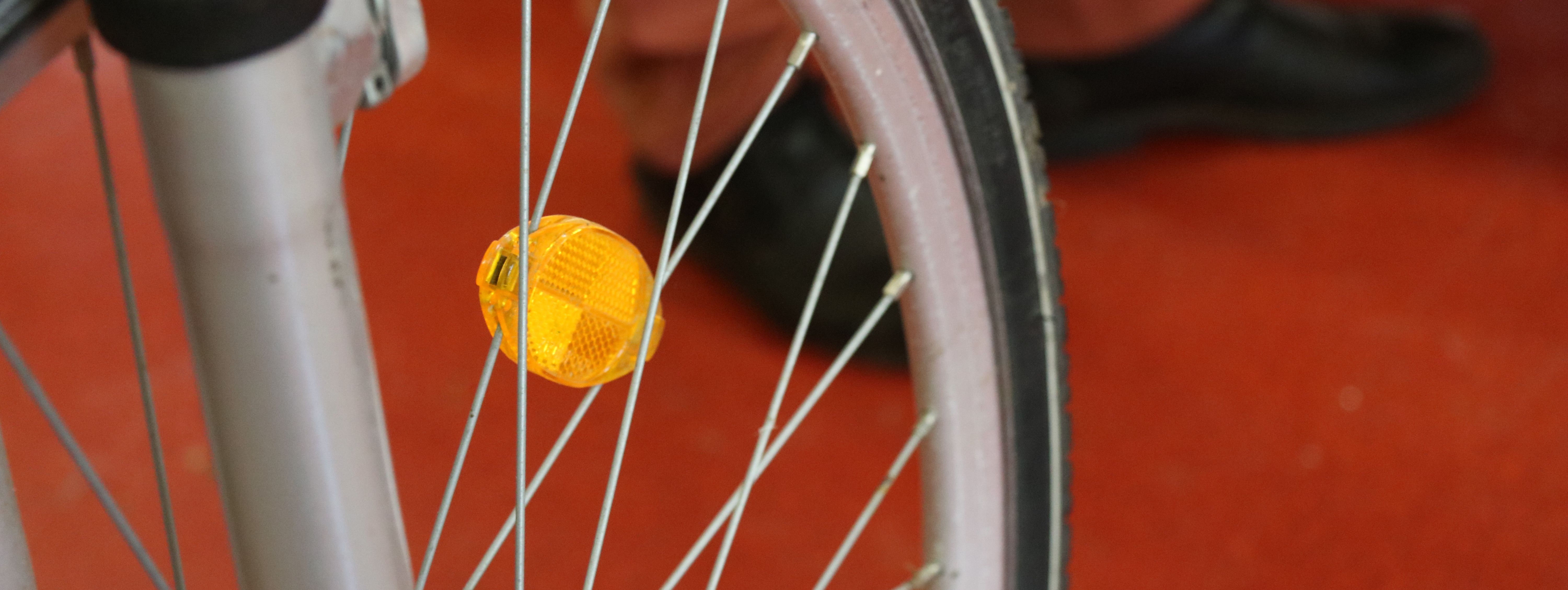 Das Speichenrad eines Fahrrades mit einem gelben Reflektor