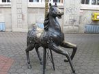 Zu sehen ist das Kirmesdenkmal in Menden beim Alten Rathaus. Es handelt sich um ein Karusselpferd aus Bronze.