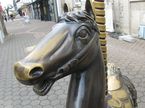 Zu sehen ist das Kirmesdenkmal in Menden beim Alten Rathaus. Es handelt sich um ein Karusselpferd aus Bronze. Das Foto zeigt eine Nahaufnahme des Kopfes.