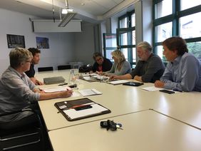 Einige Mitglieder der Arbeitsgruppe "Inhalte Bürgerhaus" sitzen gemeinsam an einem Tisch und diskutieren