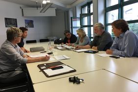 Einige Mitglieder der Arbeitsgruppe "Inhalte Bürgerhaus" sitzen gemeinsam an einem Tisch und diskutieren