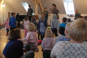 Vor der Bühne im Westflügel der Musikschule stehen Kinder und schauen, was die Musiker und "Hanna Fuchsfuß" auf der Bühne machen.