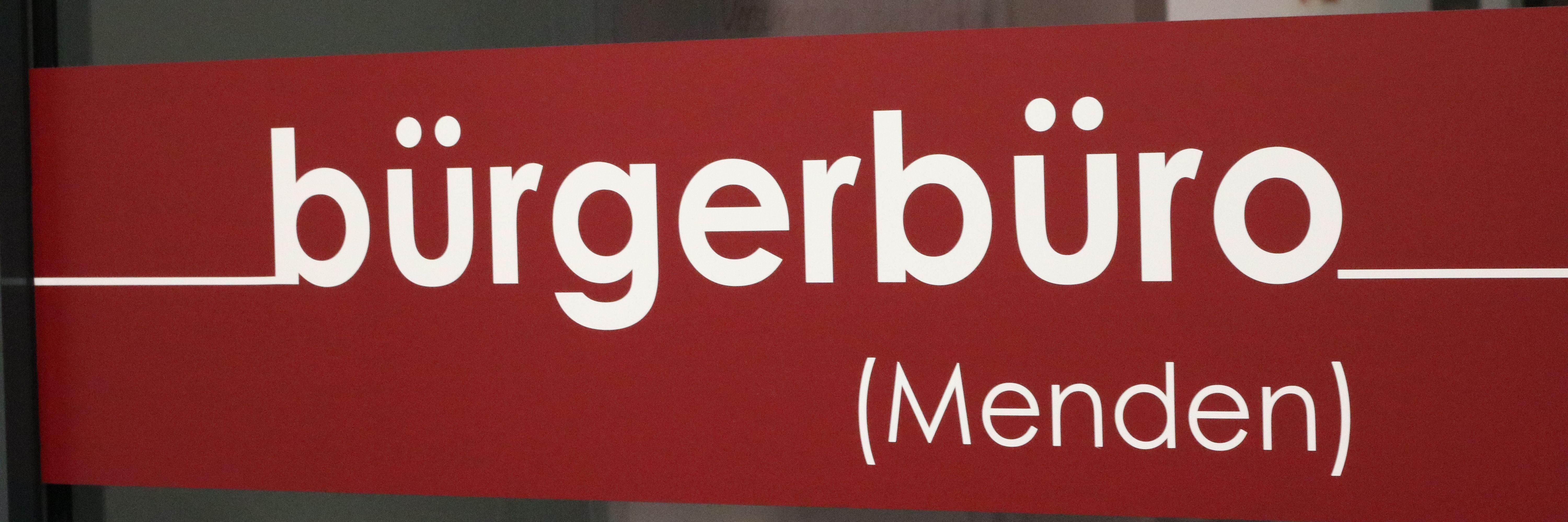 Der rote Aufkleber an der Eingangstür zum Bürgerbüro, auf dem in weißen Buchstaben das Wort "Bürgerbüro" zu lesen ist.