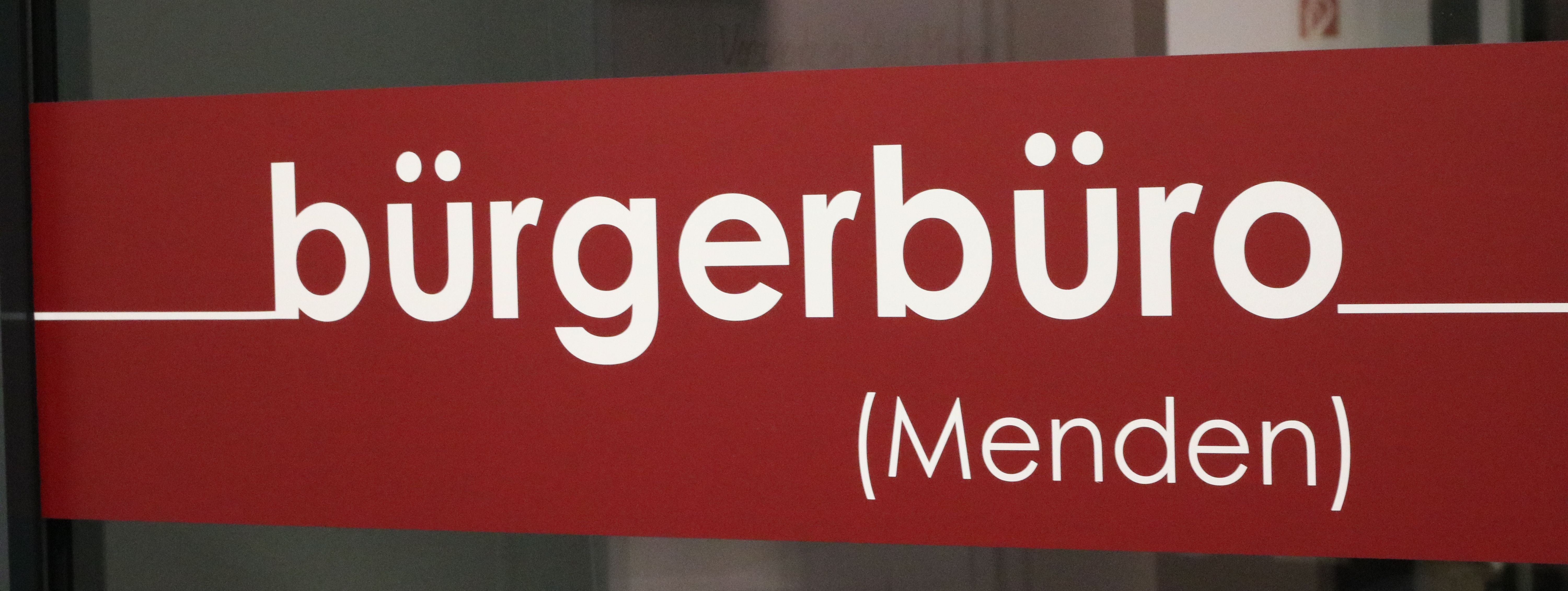 Der rote Aufkleber an der Eingangstür zum Bürgerbüro, auf dem in weißen Buchstaben das Wort "Bürgerbüro" zu lesen ist.