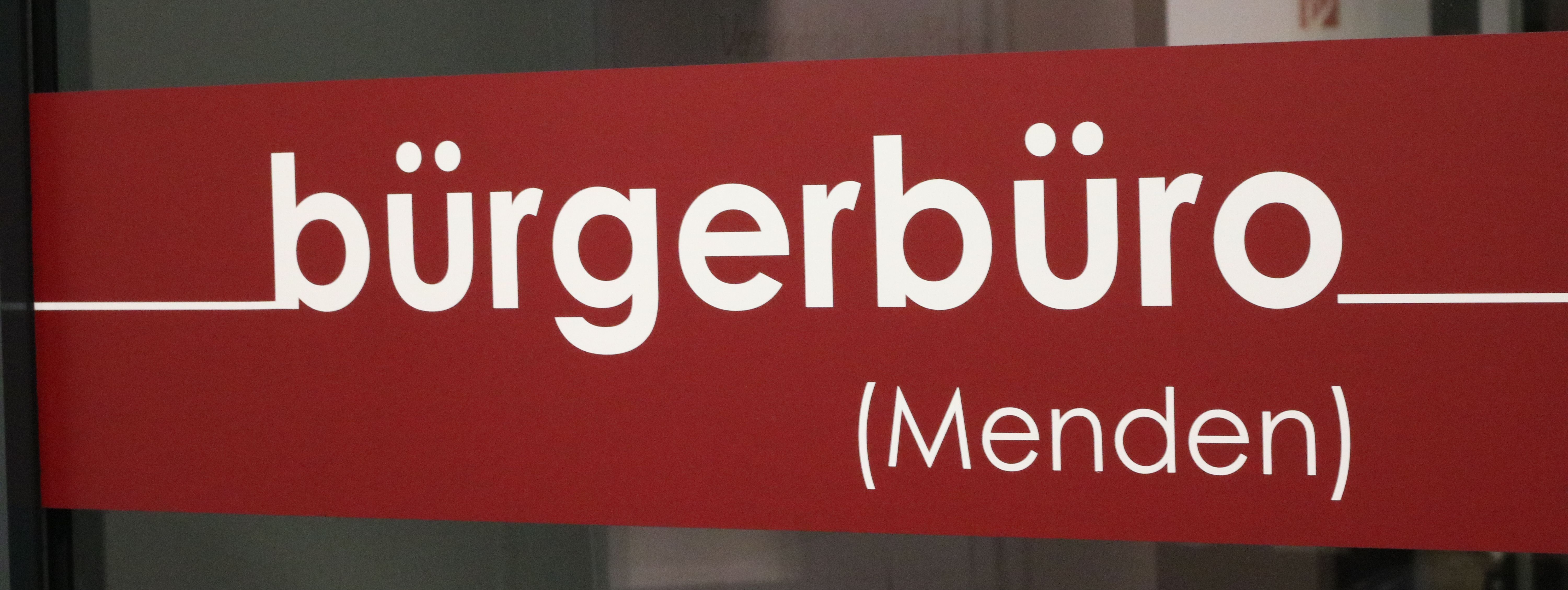 Der rote Aufkleber an der Eingangstür zum Bürgerbüro, auf dem in weißen Buchstaben das Wort "Bürgerbüro" zu lesen ist.