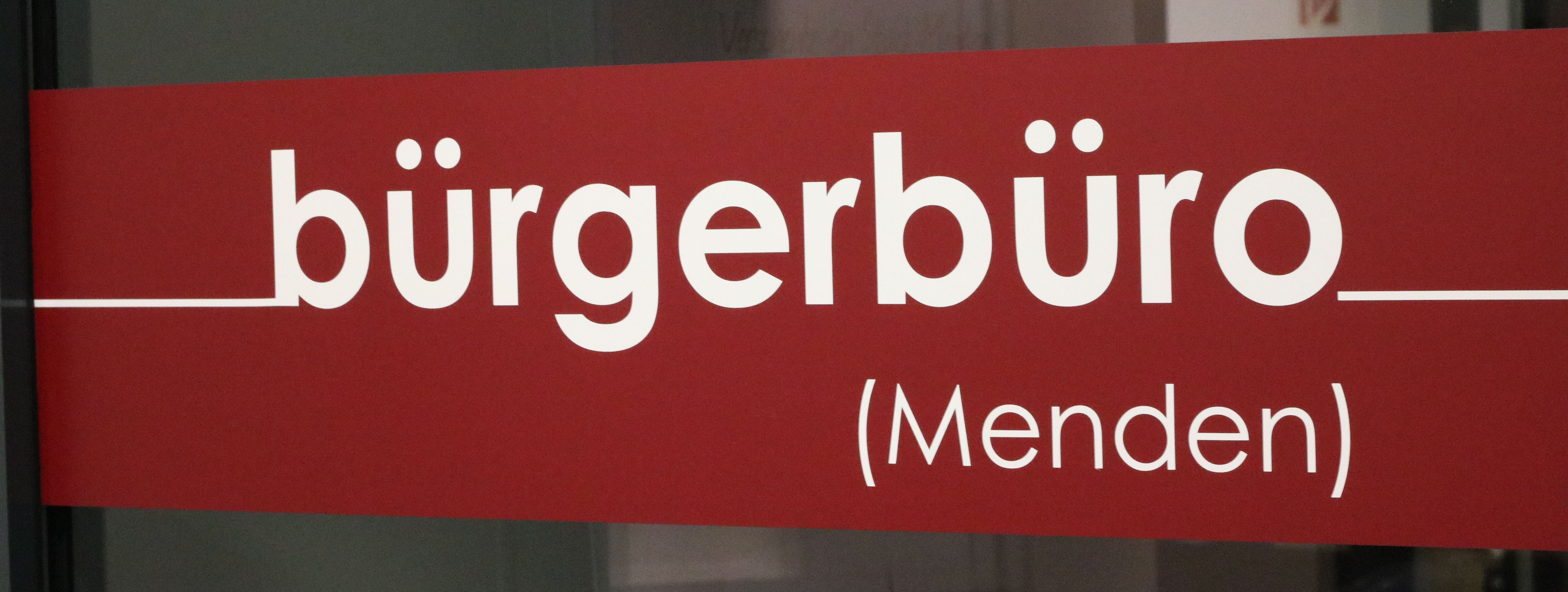 Der rote Aufkleber an der Eingangstür zum Bürgerbüro, auf dem in weißen Buchstaben das Wort "Bürgerbüro" zu lesen ist.