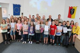 Die Schüler stehen im Ratssaal des Neuen Rathauses in Menden, einige halten ihre Urkunden in den Händen.