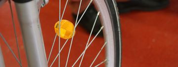 Das Speichenrad eines Fahrrades mit einem gelben Reflektor