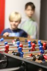 Im Vordergrund ein Kicktertisch, im Hintergrund unscharf Kinder 