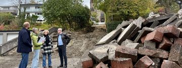 Baudezernent Tobias Wilms und Dagmar Gerling, Teamleiterin Bauen der Abteilung Straßenbau und Verkehr, zeigen Bürgermeister Dr. Roland Schröder und Manuela Schmidt die Pläne der jetzt beginnenden Baumaßnahme der Lebensader Lendringsen Mitte sowie die ersten Arbeiten am Treppenaufgangs zur Kir-che St. Josef.