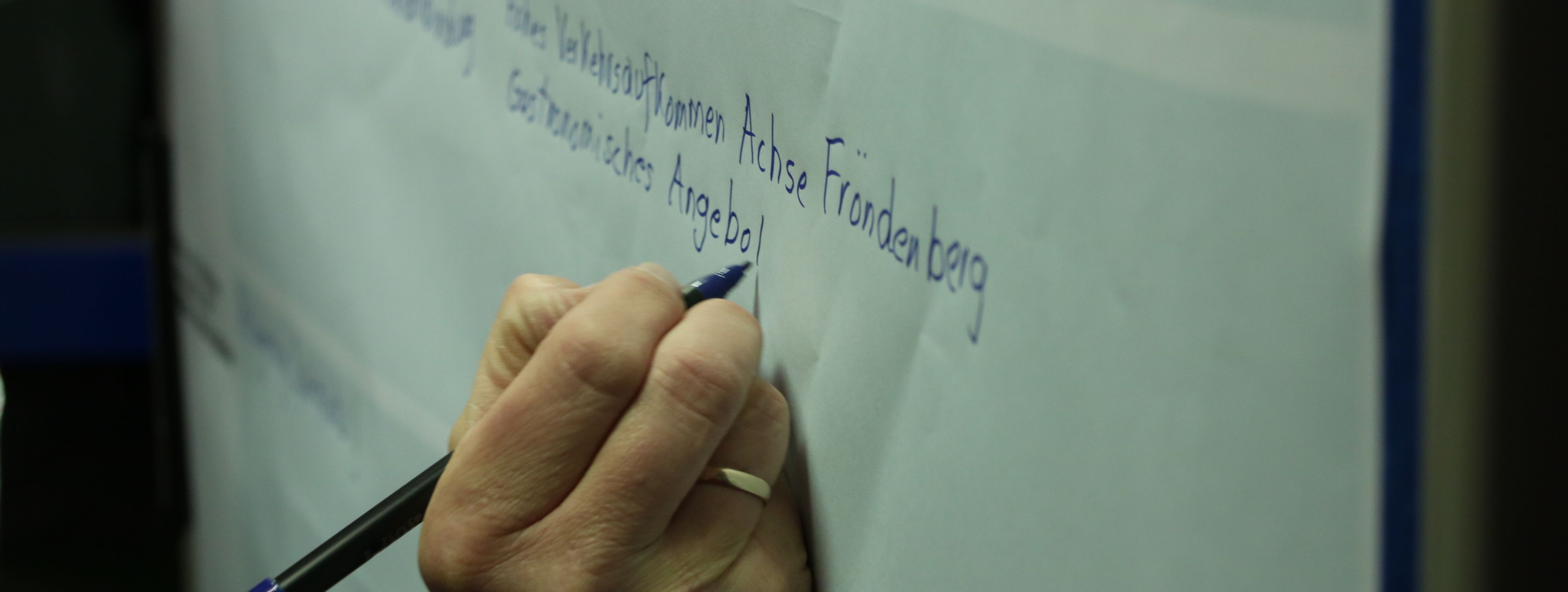 Hand mit Filzstift schreibt auf Plakat