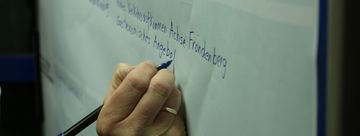 Hand mit Filzstift schreibt auf Plakat