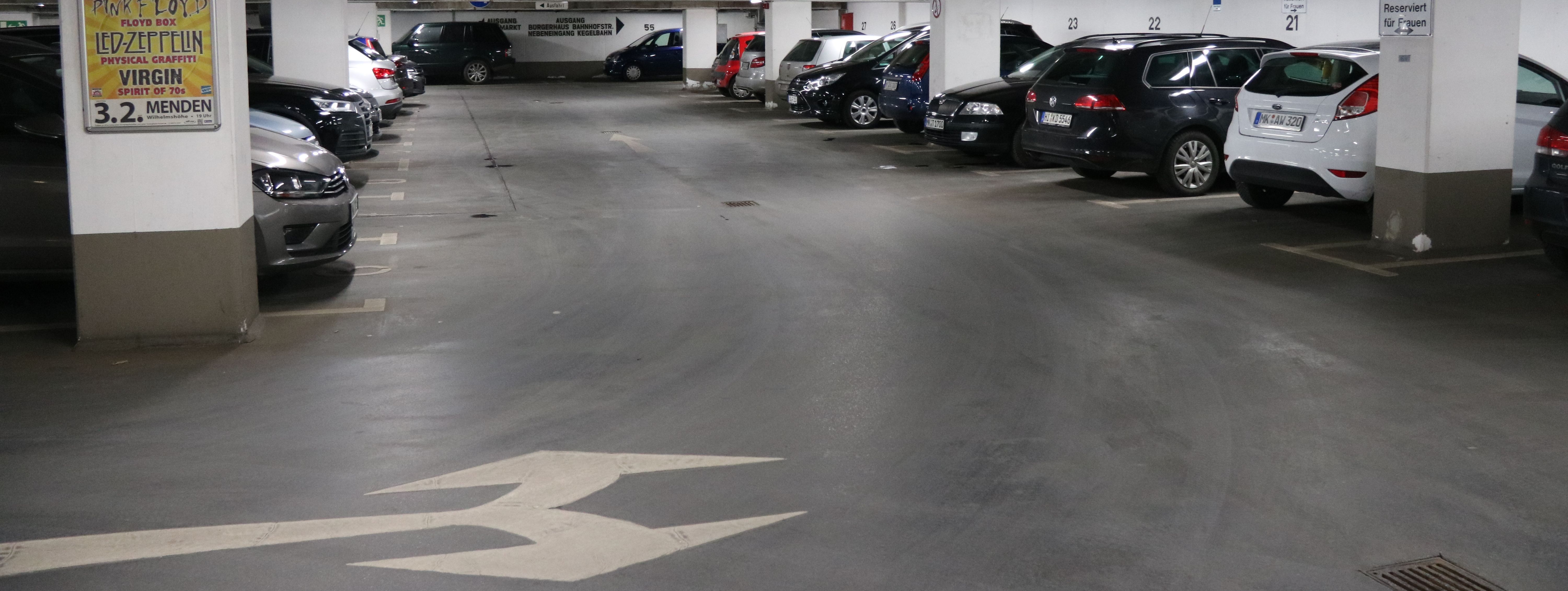 Die Tiefgarage unter dem Rathaus am Neumarkt. In mehreren Reihen parken hier Autos. Zwischen den Parkboxen sind in regelmäßigen Abständen weiße Säulen, die die Decke stützen.