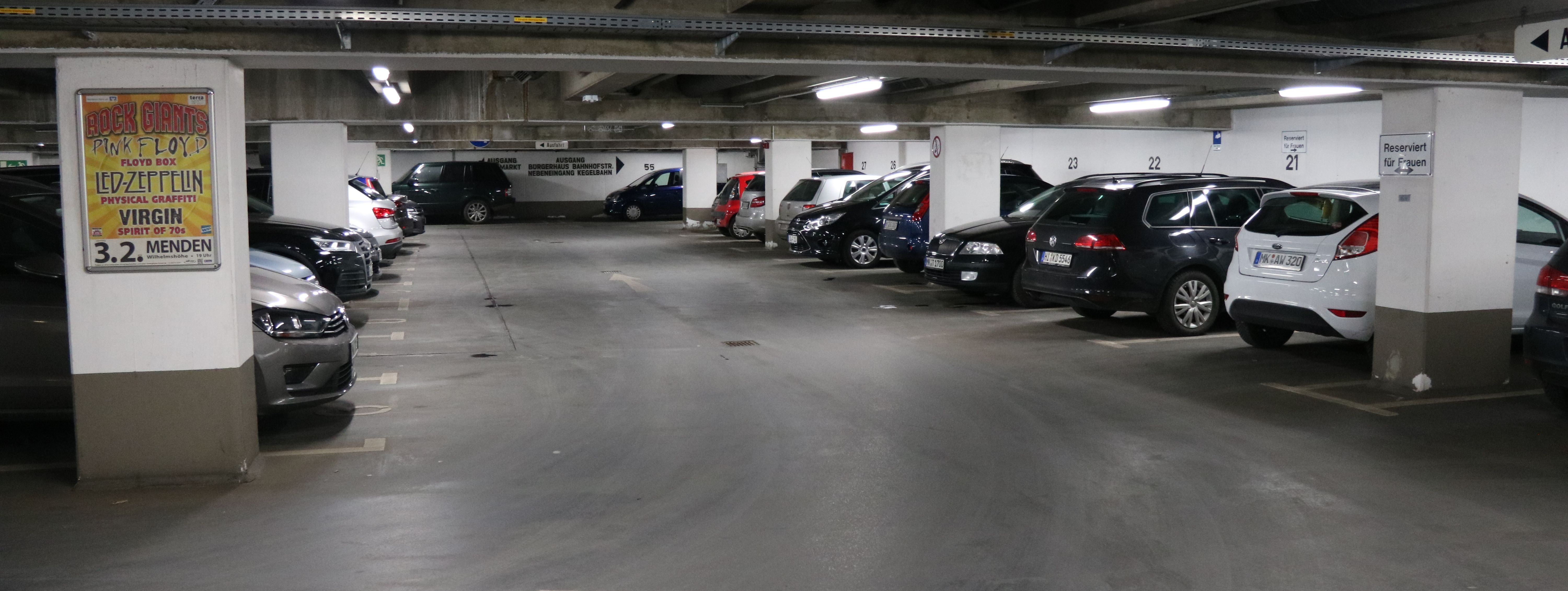 Die Tiefgarage unter dem Rathaus am Neumarkt. In mehreren Reihen parken hier Autos. Zwischen den Parkboxen sind in regelmäßigen Abständen weiße Säulen, die die Decke stützen.