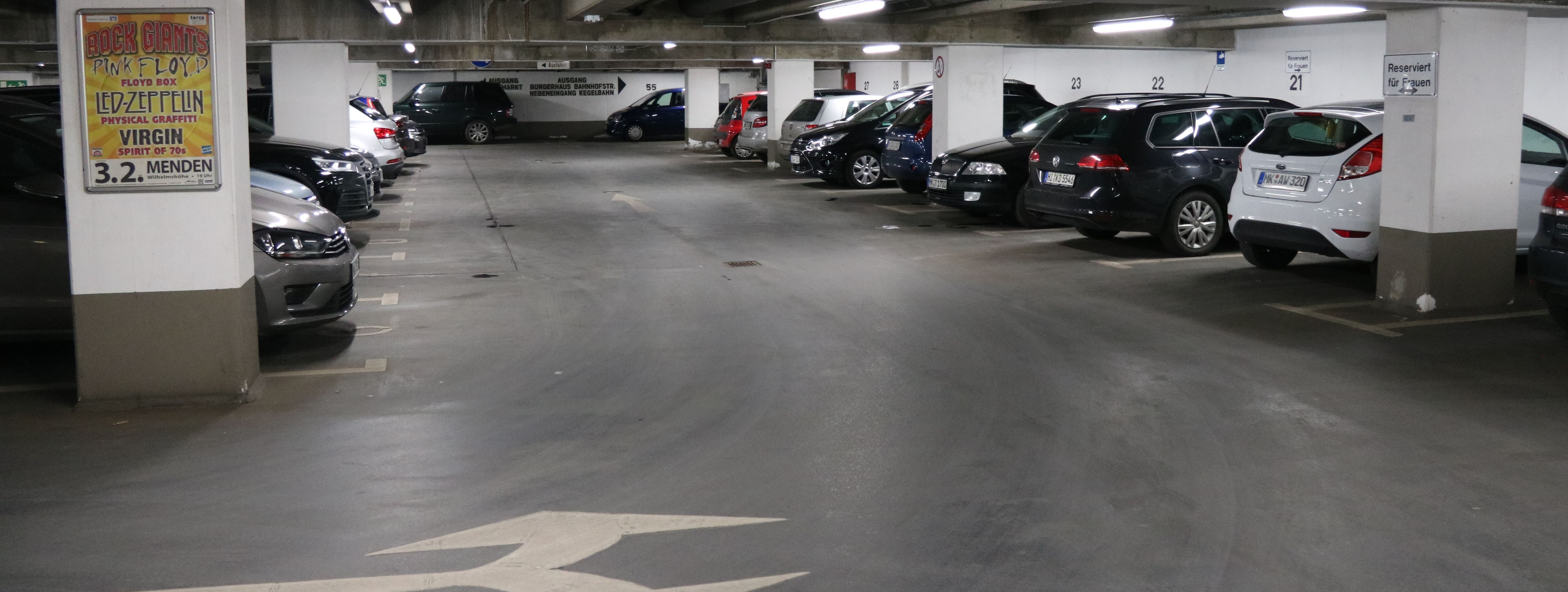 Die Tiefgarage unter dem Rathaus am Neumarkt. In mehreren Reihen parken hier Autos. Zwischen den Parkboxen sind in regelmäßigen Abständen weiße Säulen, die die Decke stützen.