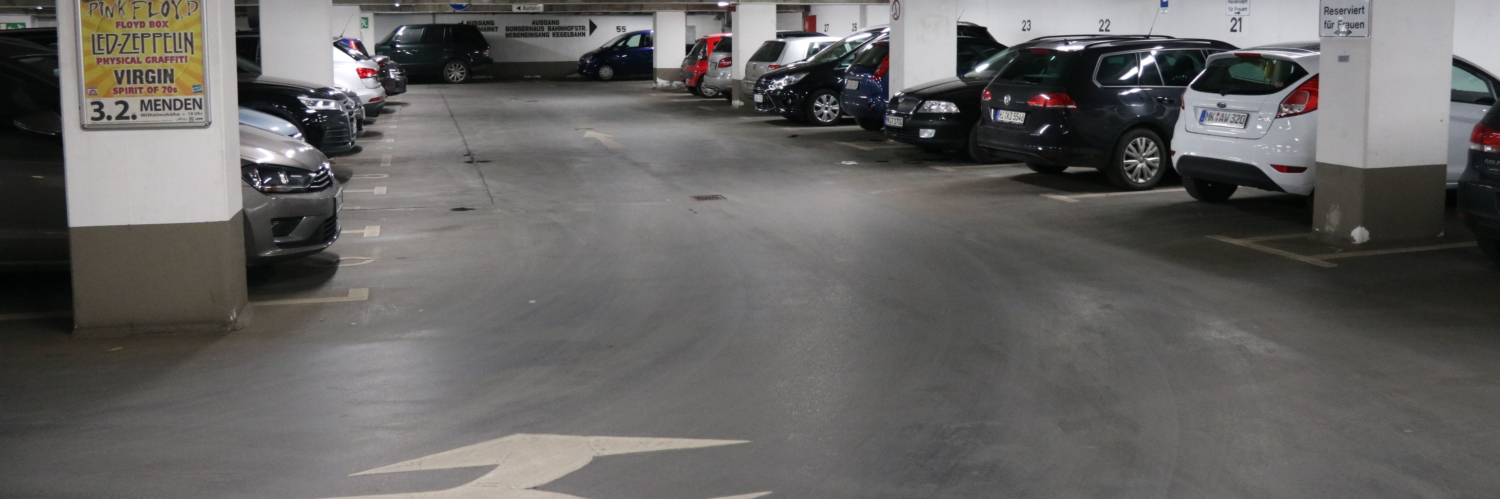 Die Tiefgarage unter dem Rathaus am Neumarkt. In mehreren Reihen parken hier Autos. Zwischen den Parkboxen sind in regelmäßigen Abständen weiße Säulen, die die Decke stützen.