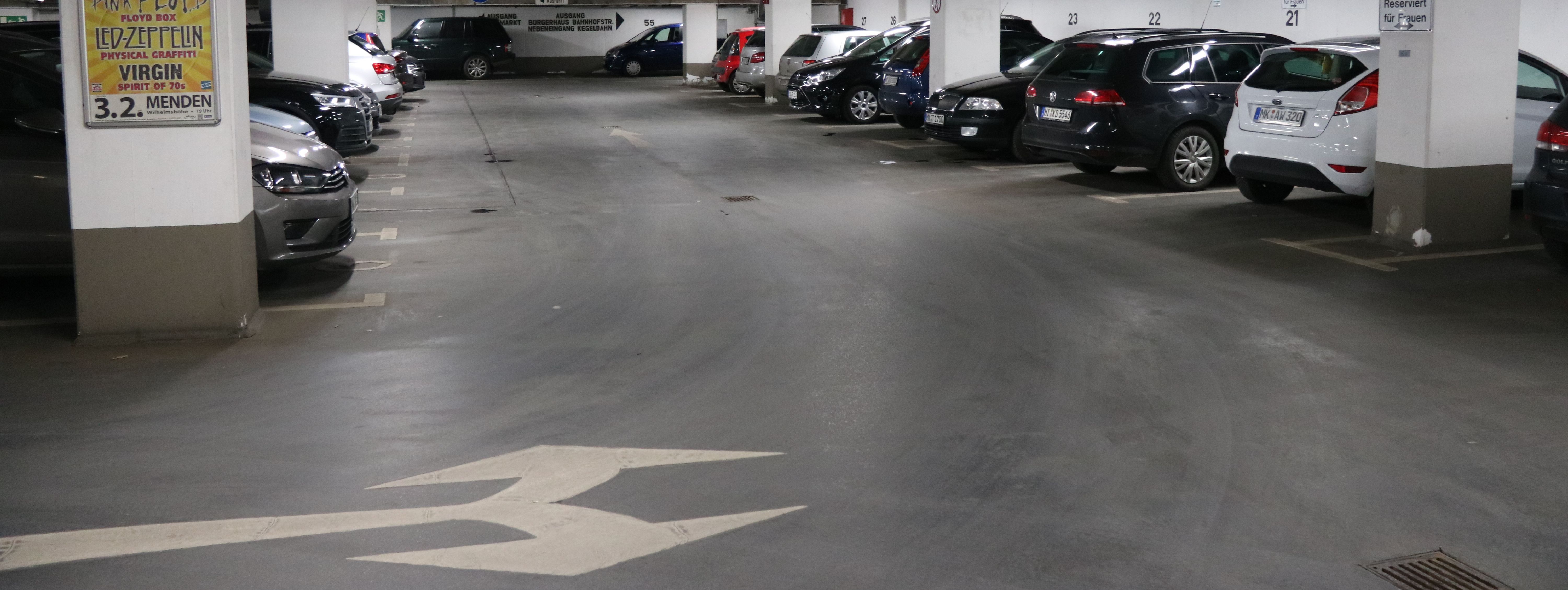 Die Tiefgarage unter dem Rathaus am Neumarkt. In mehreren Reihen parken hier Autos. Zwischen den Parkboxen sind in regelmäßigen Abständen weiße Säulen, die die Decke stützen.