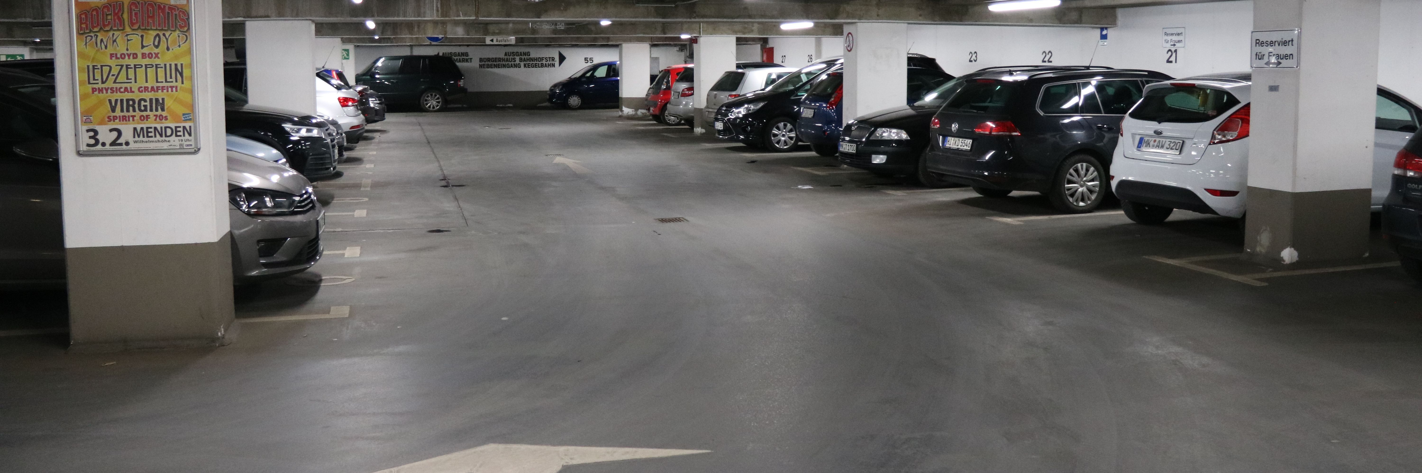 Die Tiefgarage unter dem Rathaus am Neumarkt. In mehreren Reihen parken hier Autos. Zwischen den Parkboxen sind in regelmäßigen Abständen weiße Säulen, die die Decke stützen.