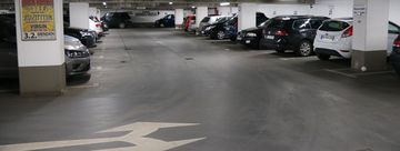 Die Tiefgarage unter dem Rathaus am Neumarkt. In mehreren Reihen parken hier Autos. Zwischen den Parkboxen sind in regelmäßigen Abständen weiße Säulen, die die Decke stützen.