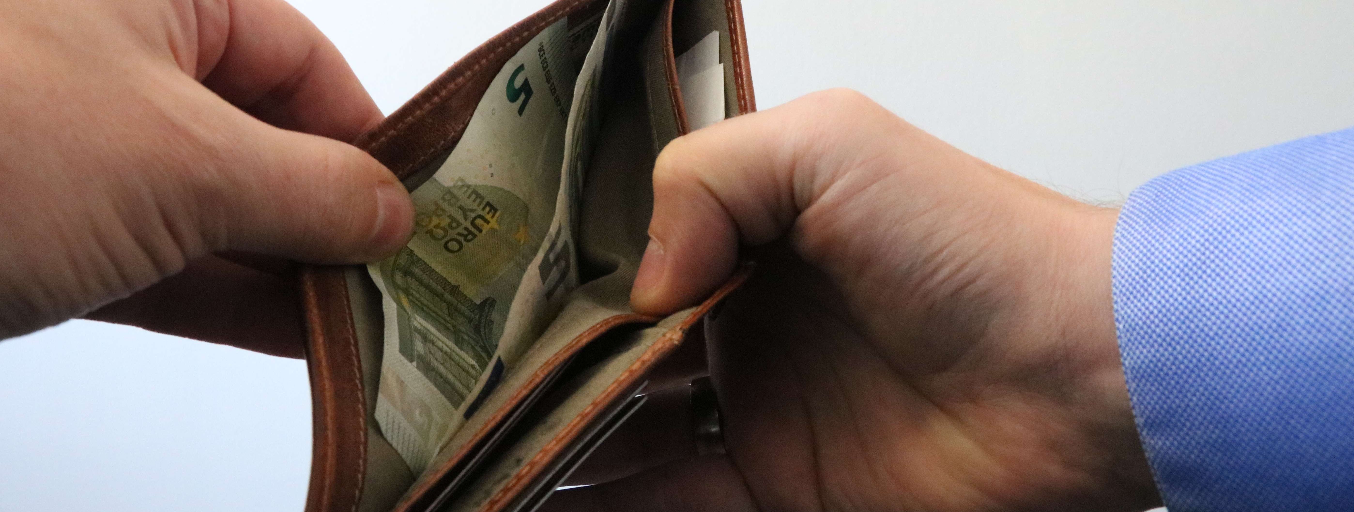 Zwei Hände öffnen ein Portemonnaie.