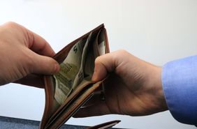 Zwei Hände öffnen ein Portemonnaie.