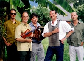 Die fünf Musiker von Le Clou stehen vor einem karibischen Hintergrund mit Palmen, einer hält eine Geige im Arm, ein anderer ein Akkordeon, ein dritter hat sich ein waschbrettartiges Instrumment um den Hals gehängt