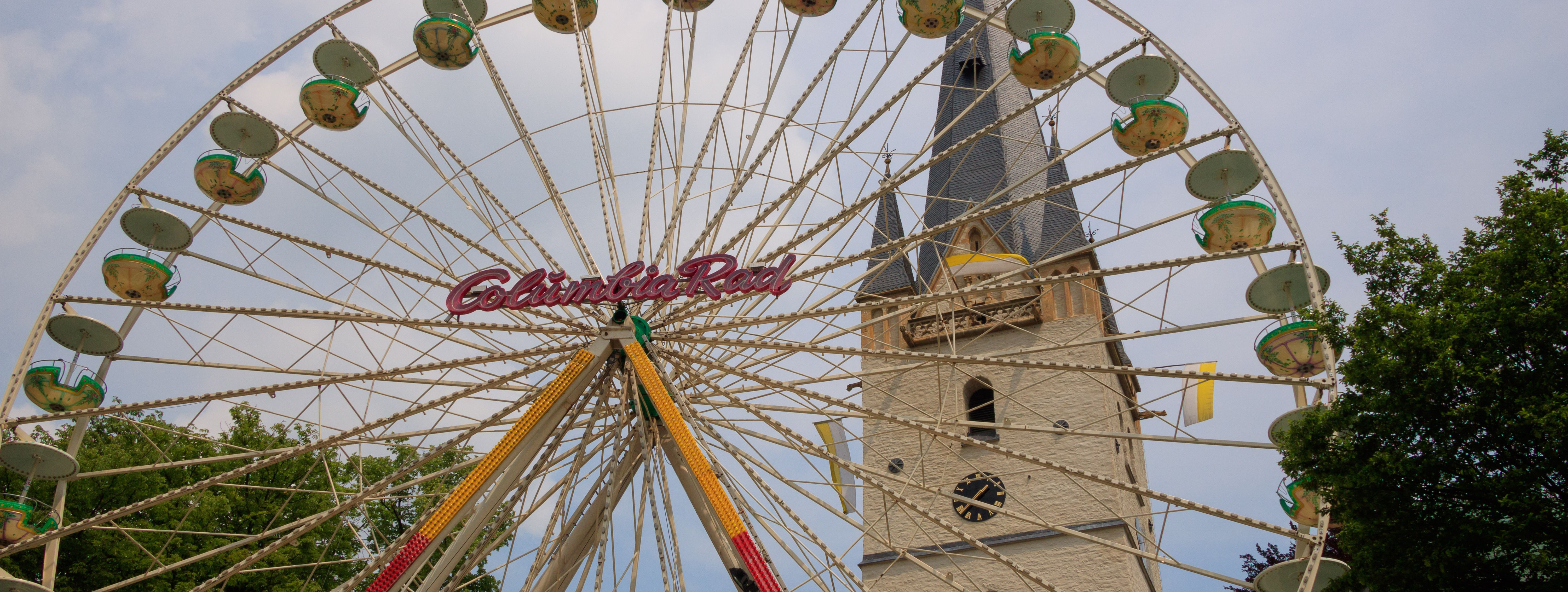 Vor dem Turm von St. Vincenz ist ein Riesenrad aufgebaut - das heimliche Wahrzeichen der Mendener Pfingskirmes