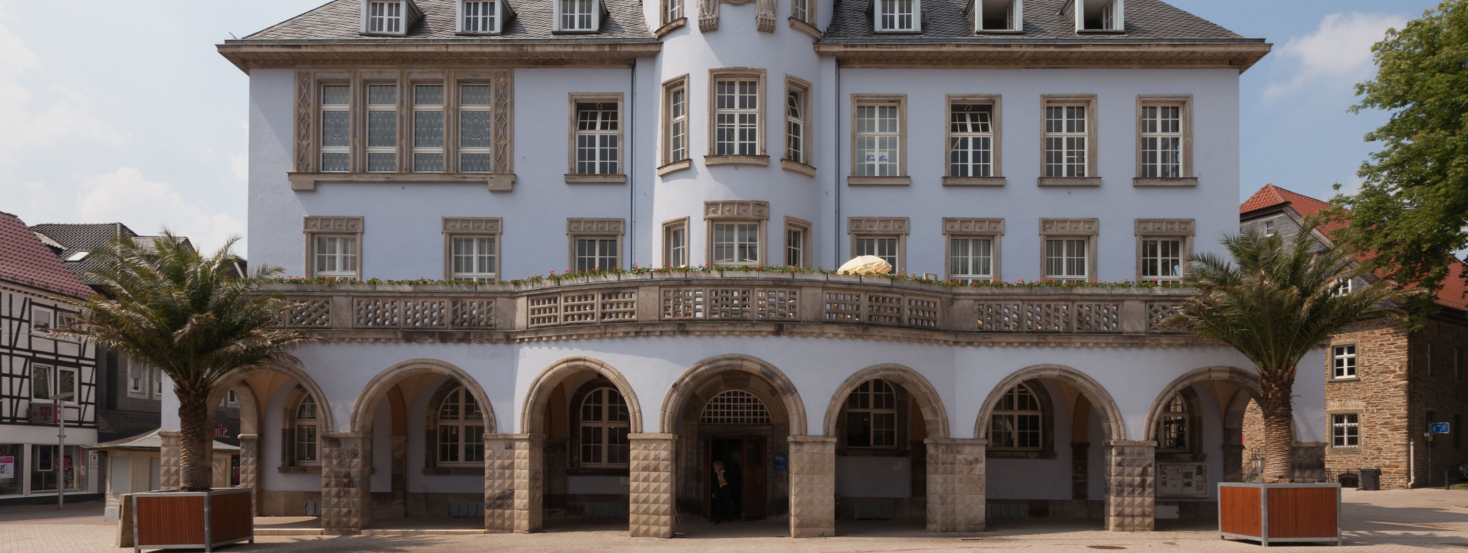 Das Alte Rathaus in Menden, graues Gebäude mit Arkaden und einem runden Turm in der Mitte