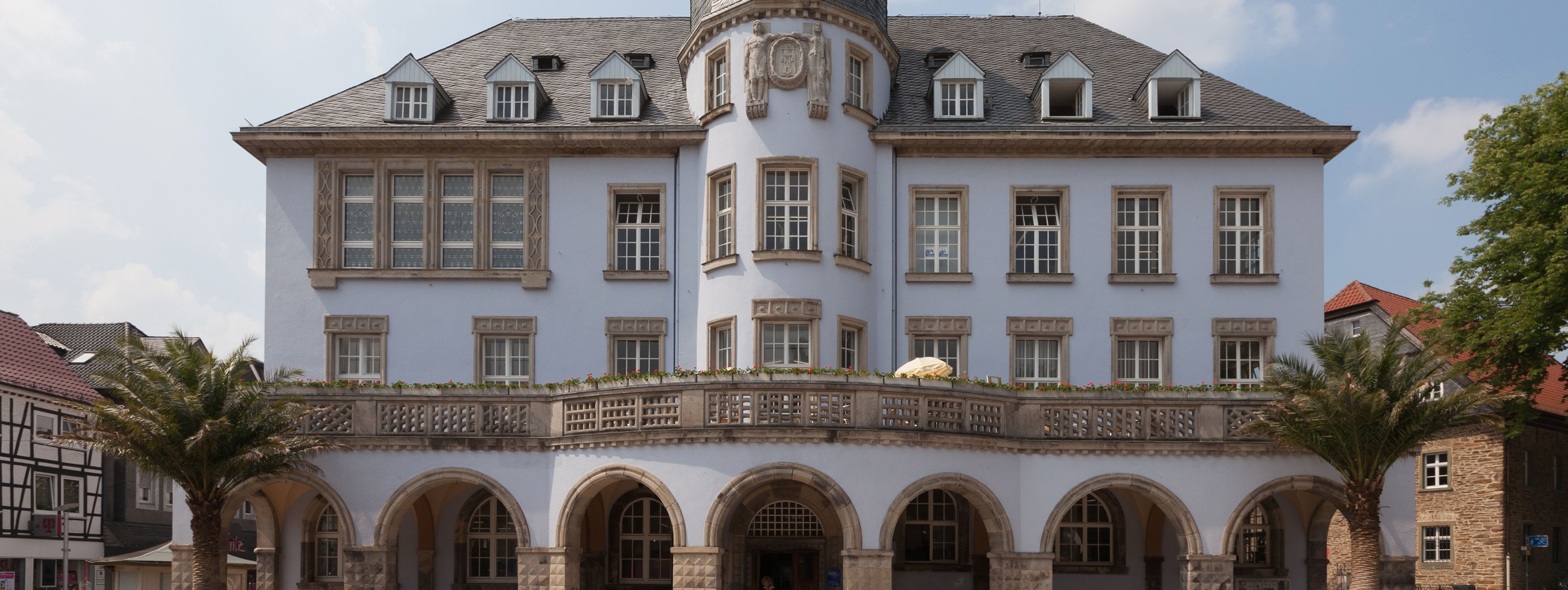 Das Alte Rathaus in Menden, graues Gebäude mit Arkaden und einem runden Turm in der Mitte