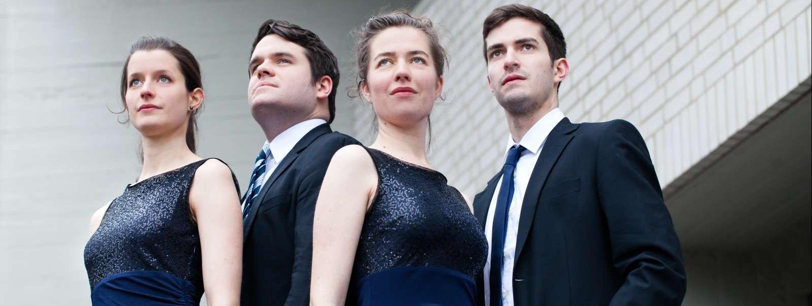 Die vier Musiker, zwei Frauen und zwei Männer, schauen in die Ferne. Die Frauen tragen beide die gleichen blauen Abendkleider, die Männer schwarze Anzüge und Krawatten.