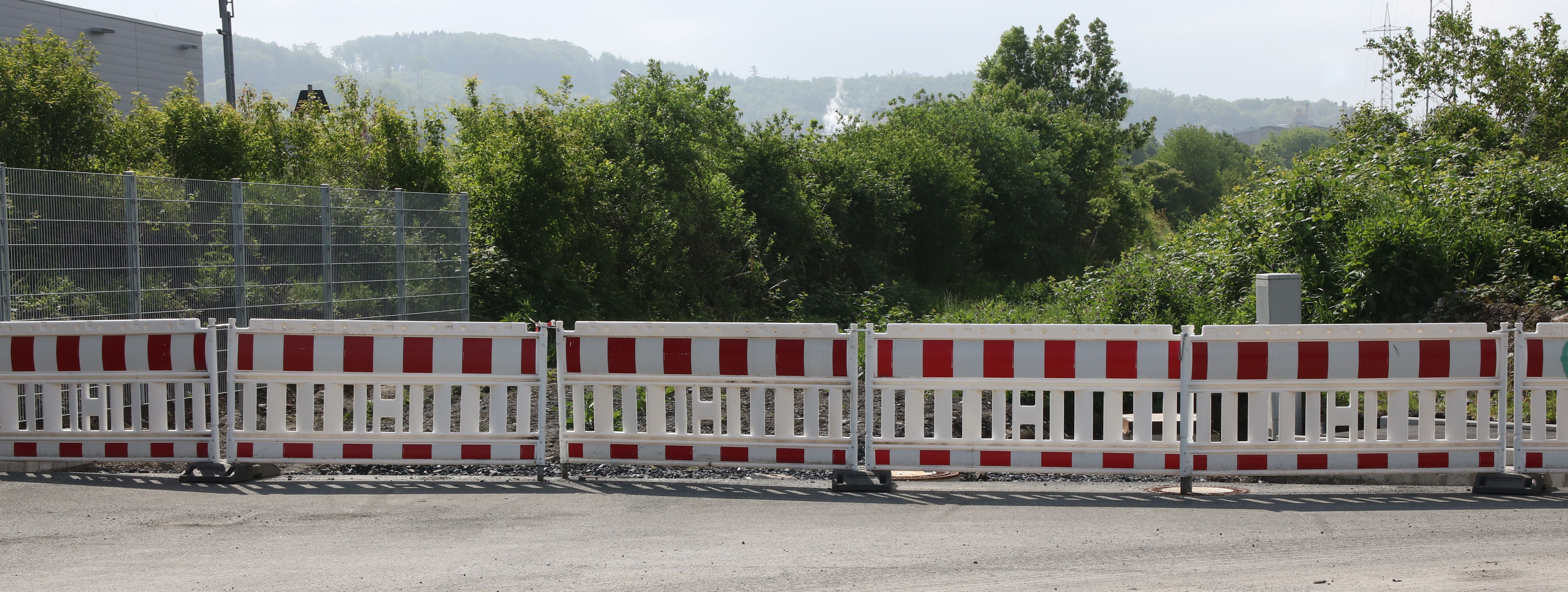 Am Ende einer neugebauten Straße steht eine reihe rot-weißer Baken zur Absperrung.