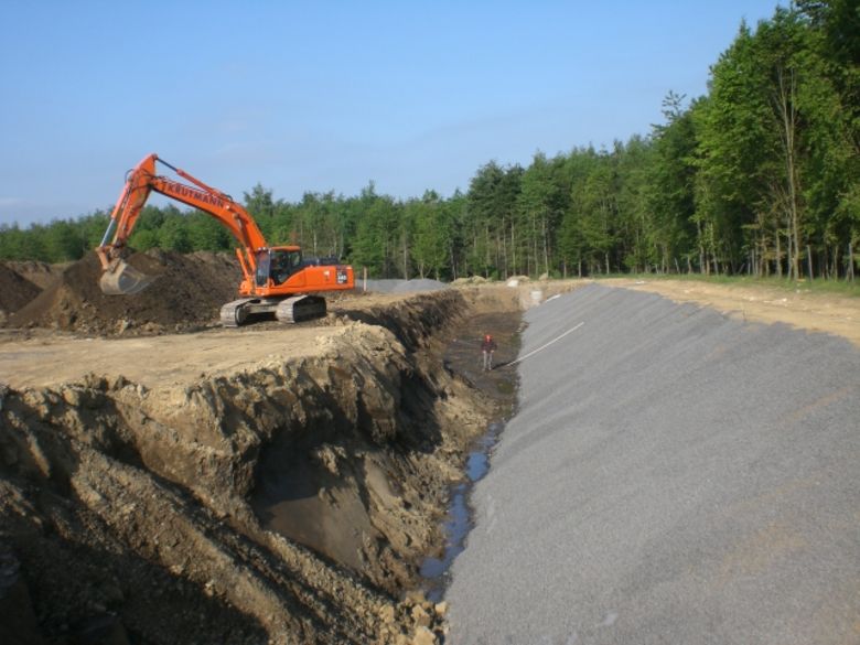 Bau des Regenrückhaltebeckens Hämmer Nord im Mai 2011. Ein Bagger hebt ein bis zu drei Meter tiefes Becken aus, die bereits fertige Seite am Nordrand ist mit Kies bedeckt.