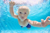 Portrait of baby boy swimming and diving underwater in pool