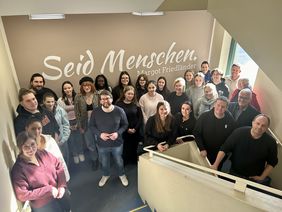 Mendener Schülerinnen und Schüler des Netzwerkes "augen auf!" vor der Inschrift des Margot Friedländer-Zitates "Seid Menschen" im Treppenhaus des Neuen Rathauses.