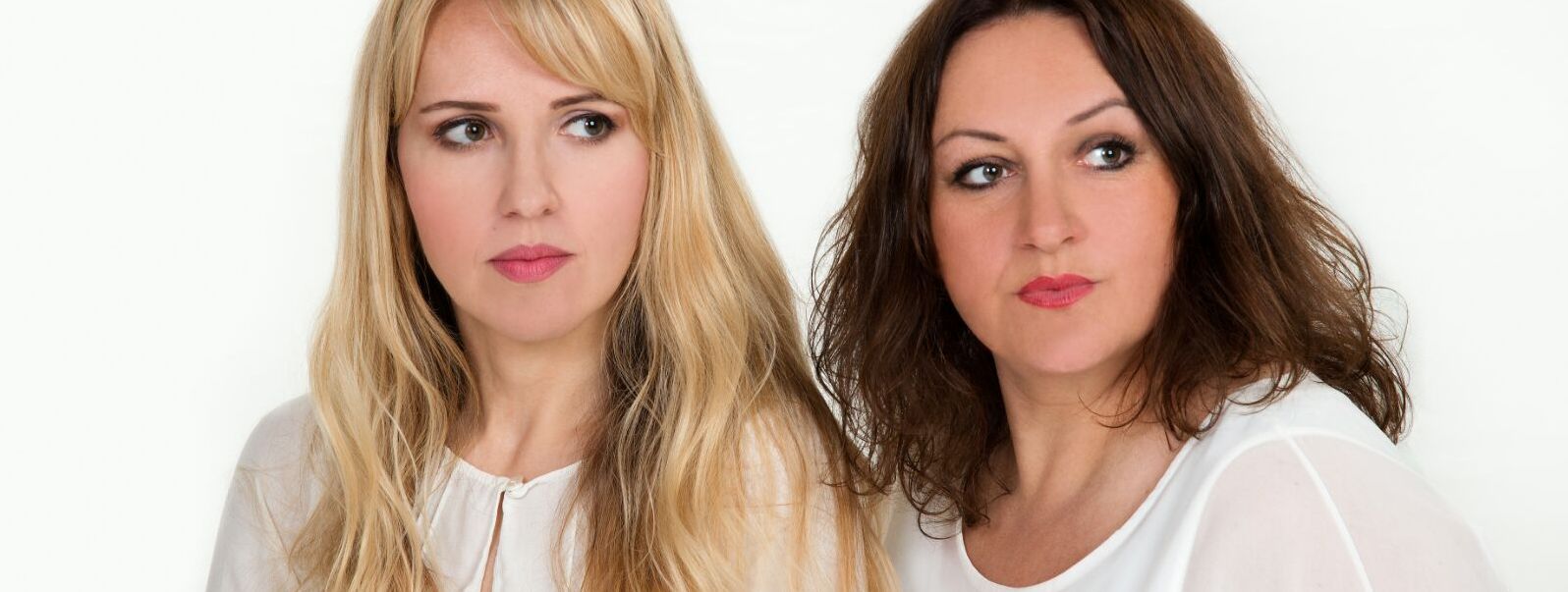 Ein Portraitfoto der beiden Musikerinnen nebeneinander. Beide tragen weiße Oberteile, Helen Blau hat blonde lange Haare, Violetta Körner hat braune lange Haare.