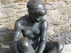 Sitzende Aktfigur aus Bronze, von vorne fotografiert.