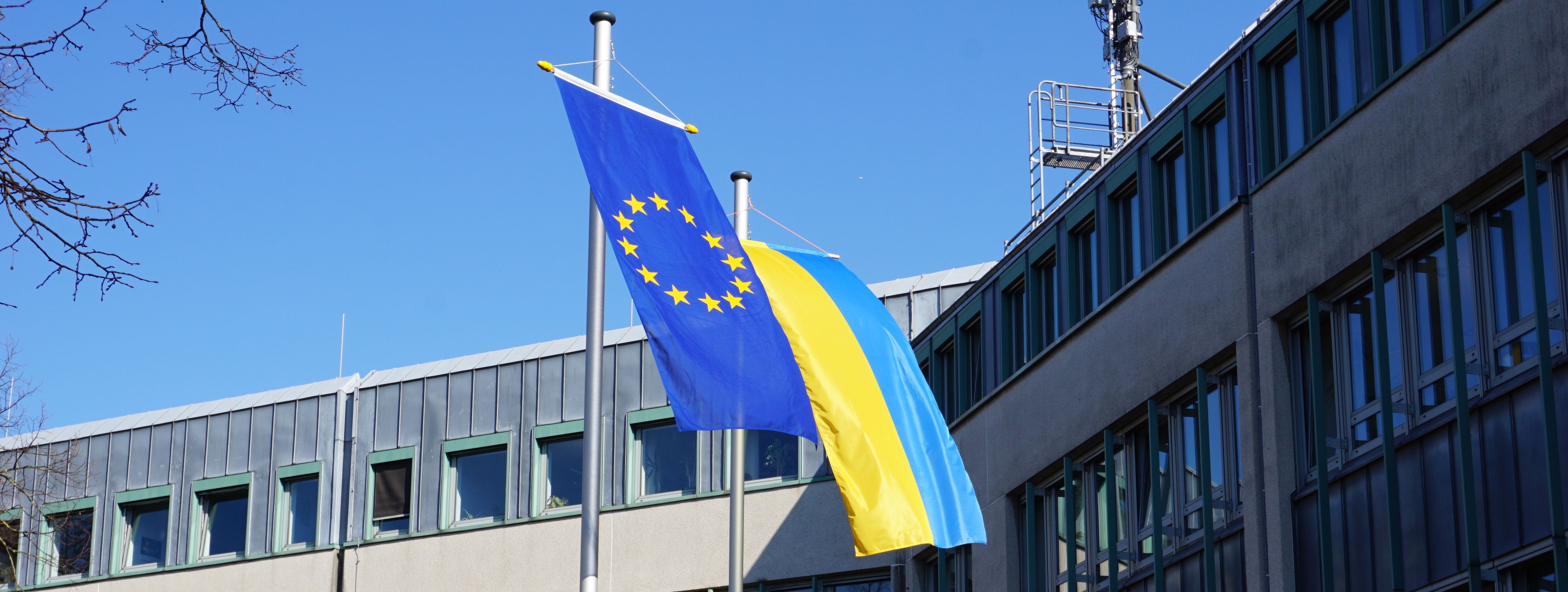 Vor dem Neuen Rathaus wehen die Flagge der Ukraine (blau/gelb) und die Europaflagge (goldene Sterne auf blauem Grund)