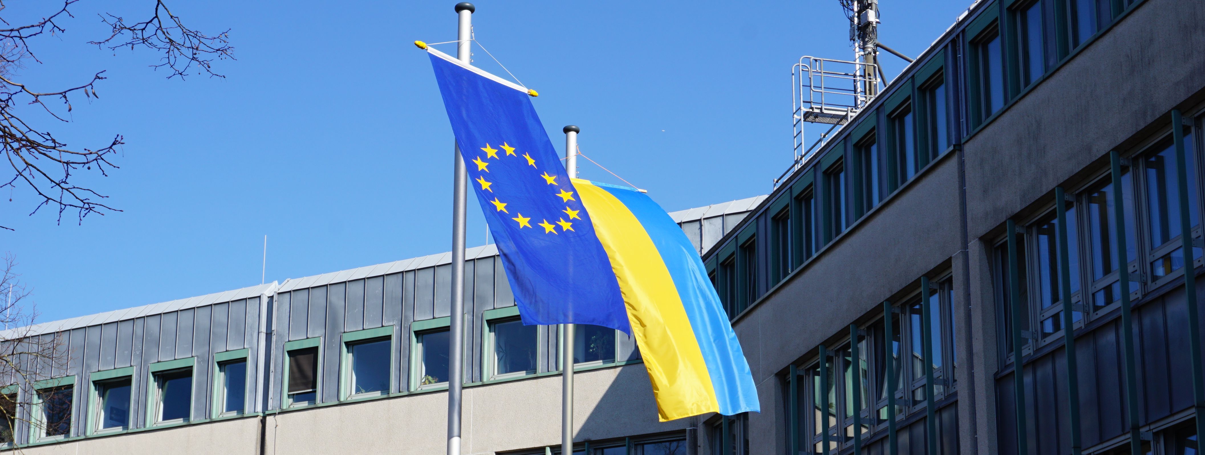 Vor dem Neuen Rathaus wehen die Flagge der Ukraine (blau/gelb) und die Europaflagge (goldene Sterne auf blauem Grund)