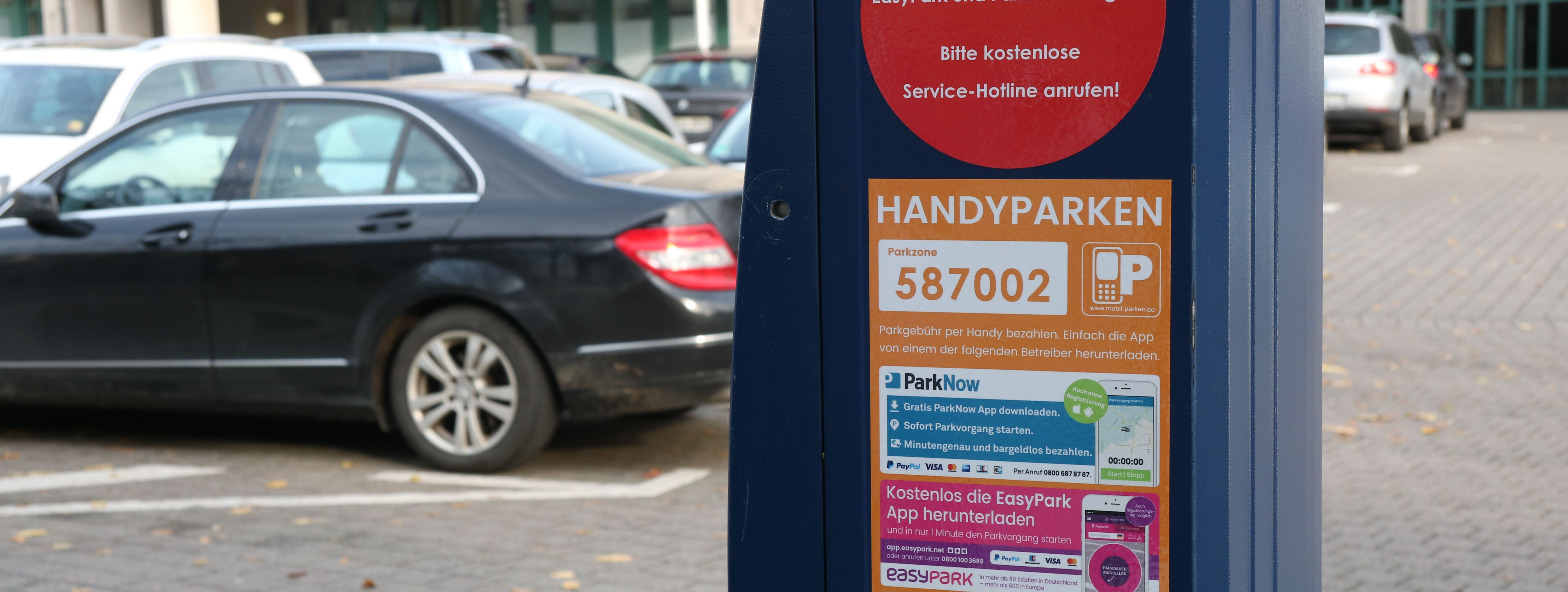 Auf dem blauen Parkscheinautomaten ist ein Aufkleber zu sehen, der das Handyparken erklärt.