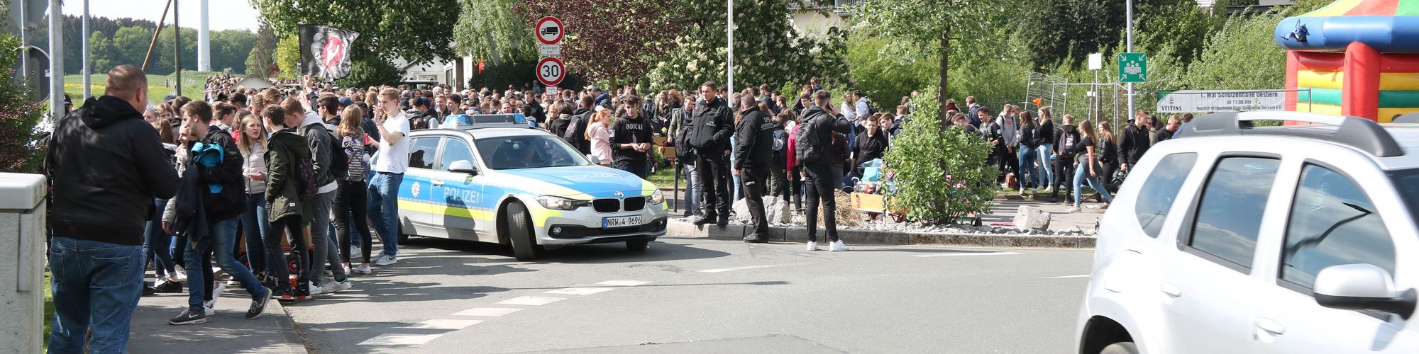 hunderte Jugendliche habe sich am Kreisverkehr in Oesbern versammelt und feiern den ersten Mai. In Mitten der Gruppe steht ein Polizeiauto.