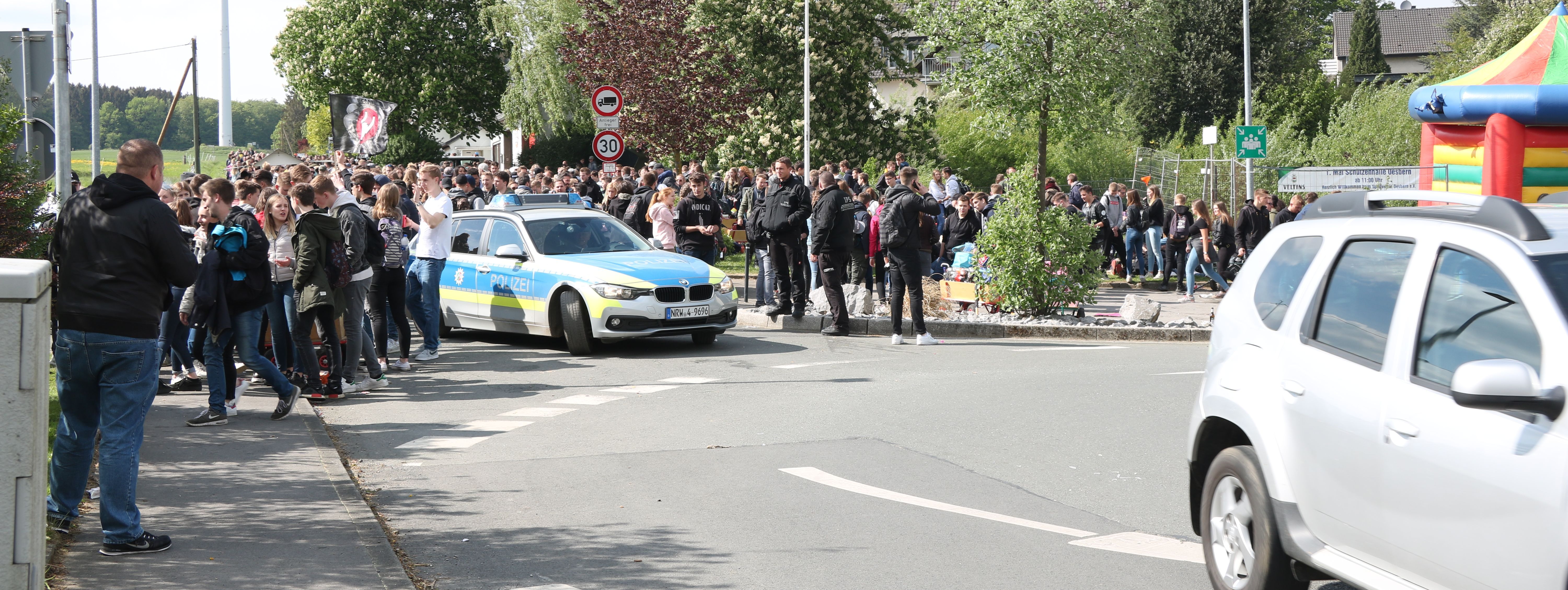 hunderte Jugendliche habe sich am Kreisverkehr in Oesbern versammelt und feiern den ersten Mai. In Mitten der Gruppe steht ein Polizeiauto.