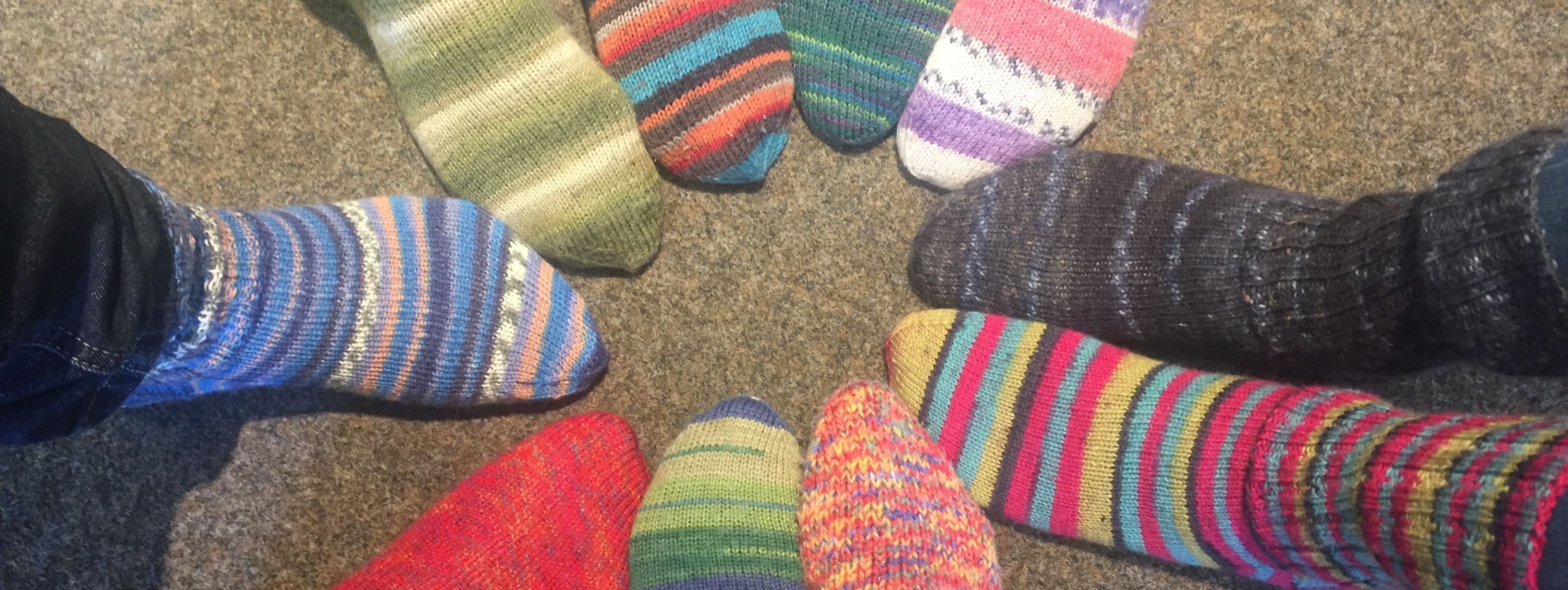 zehn Füße stecken in bunten, selbstgestrickten Wollsocken.