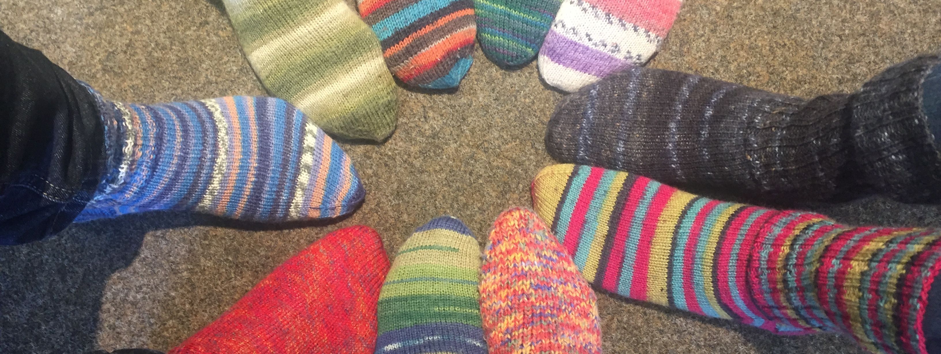 zehn Füße stecken in bunten, selbstgestrickten Wollsocken.