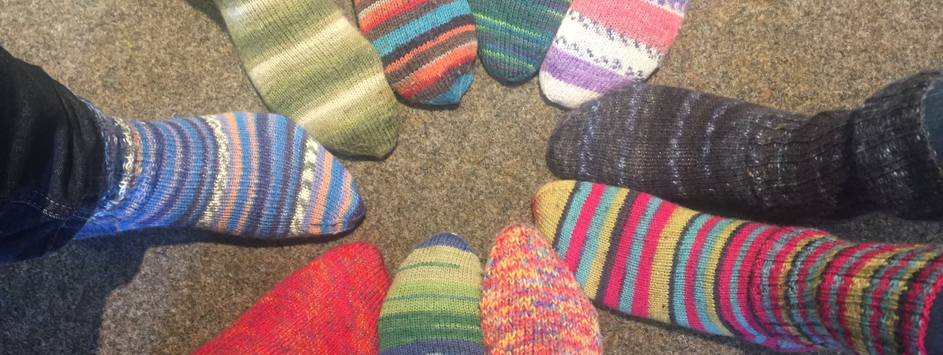 zehn Füße stecken in bunten, selbstgestrickten Wollsocken.