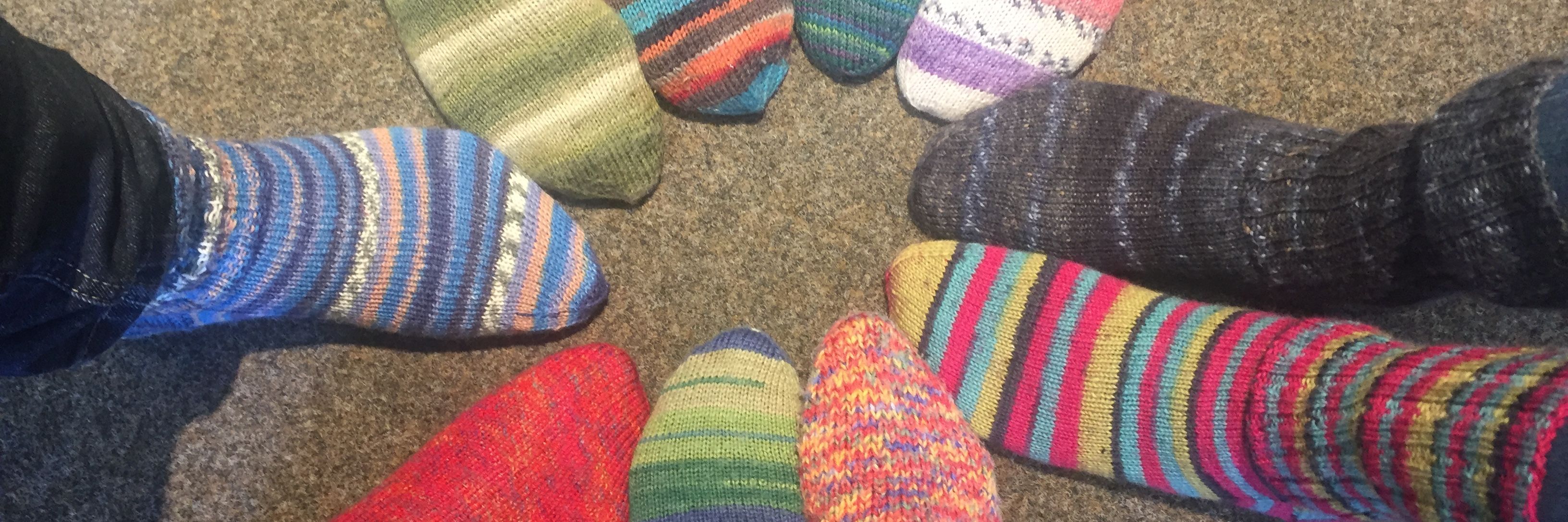 zehn Füße stecken in bunten, selbstgestrickten Wollsocken.