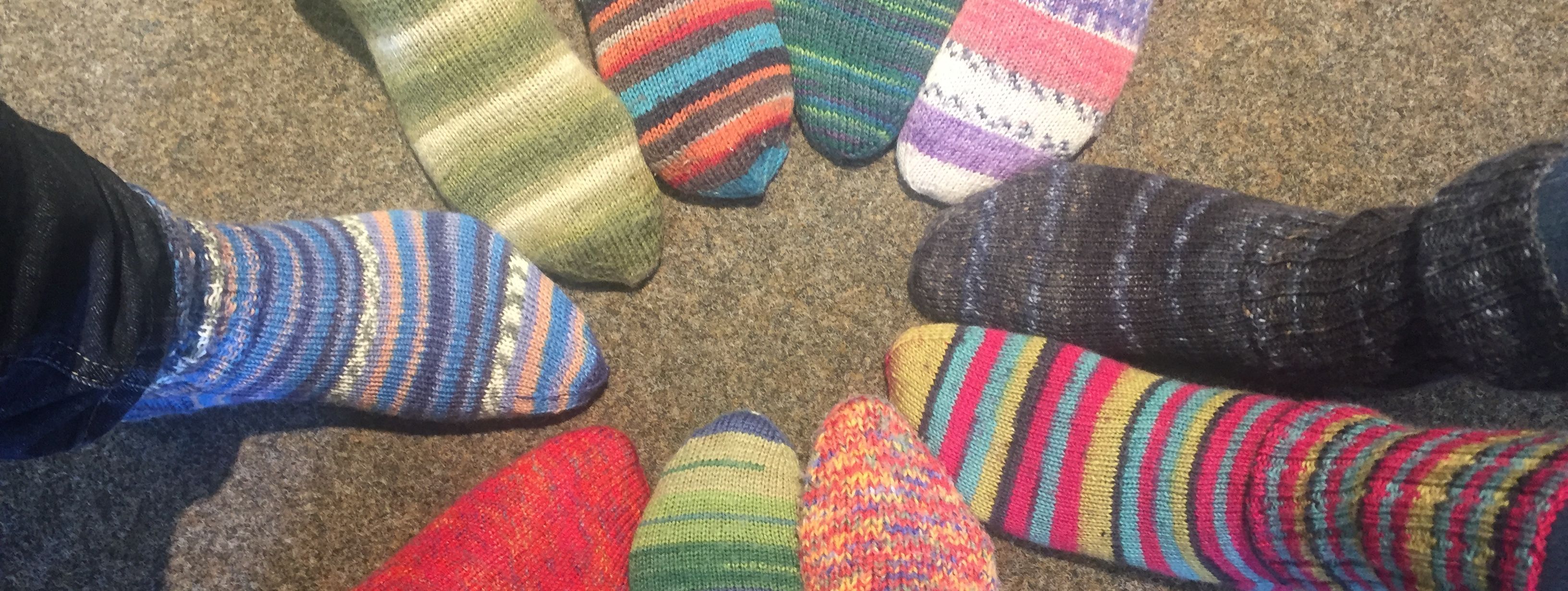 zehn Füße stecken in bunten, selbstgestrickten Wollsocken.