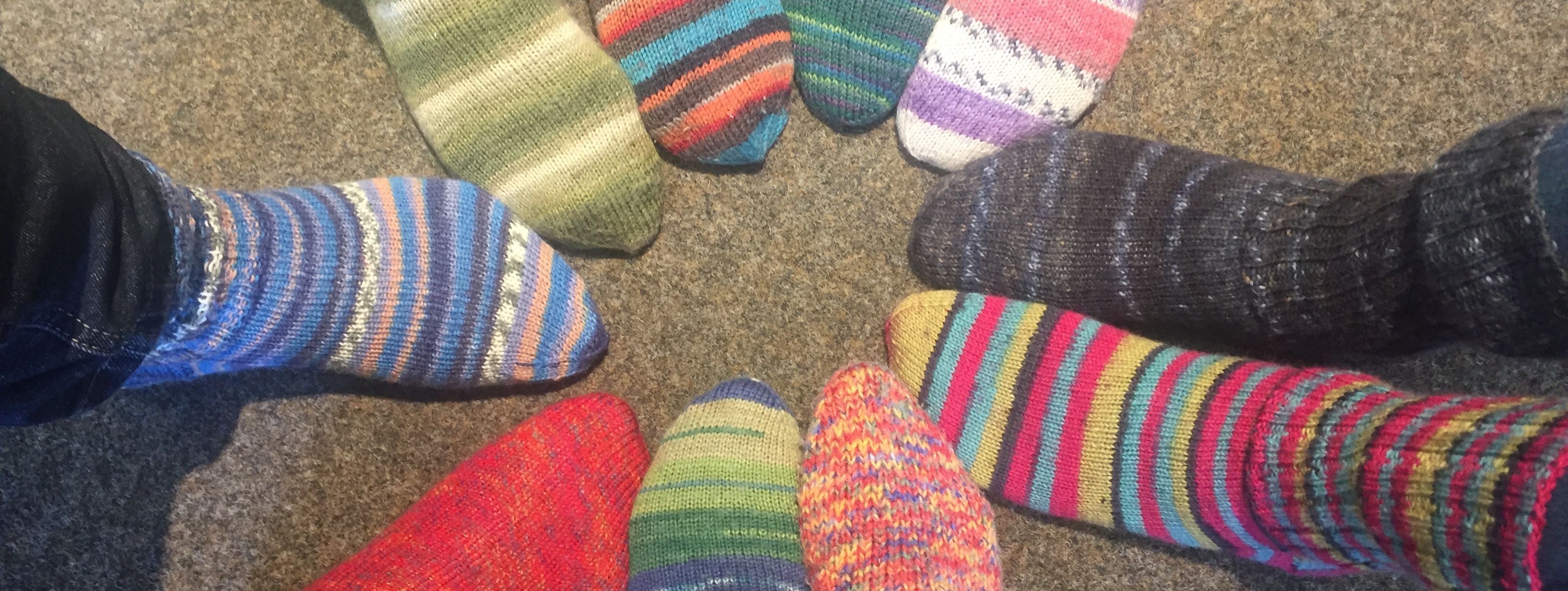 zehn Füße stecken in bunten, selbstgestrickten Wollsocken.