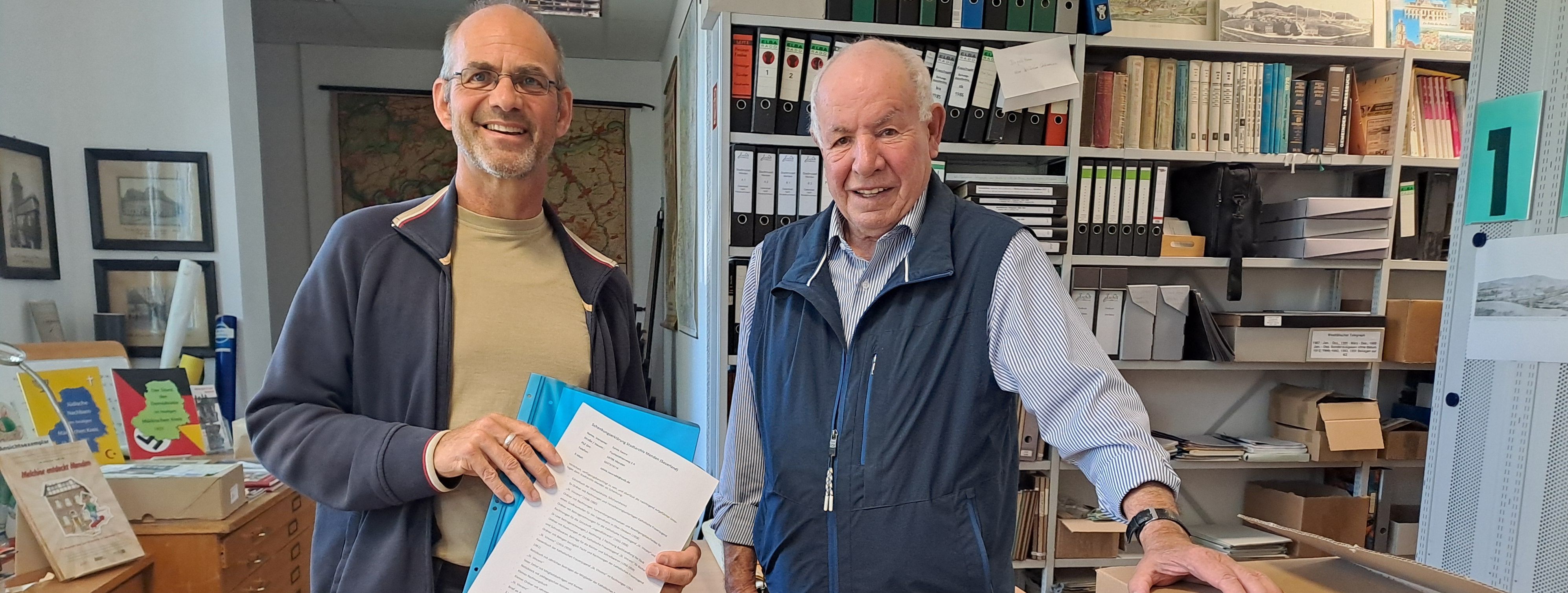 Stadtarchivar Stephan Reisloh und Elmar Dedirch stehen vor der Sammlung.