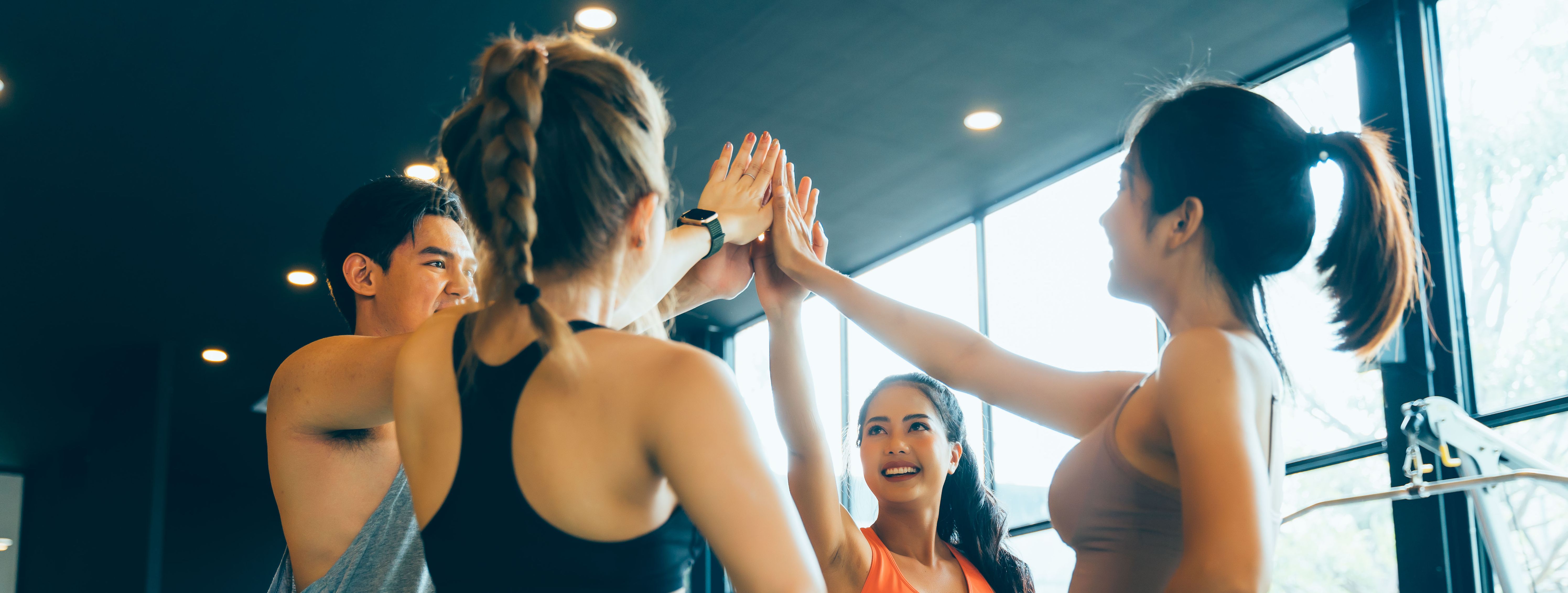Eine Gruppe von vier jungen Menschen beim Sport schlagen ihre Hände zusammen