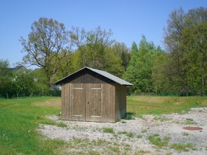 Holzhütte mit der Steuerung des Pumpwerkes im Baugebiet Abendsiepen, die Abmessungen entsprechen einem durchschnittlichen Gartenhäuschen. Das eigentliche Pumpwerk befindet sich unter einem Schachtdeckel im Vordergrund.